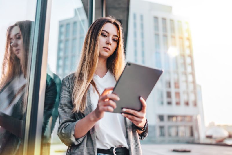 Woman standing outside working on her business from her tablet
